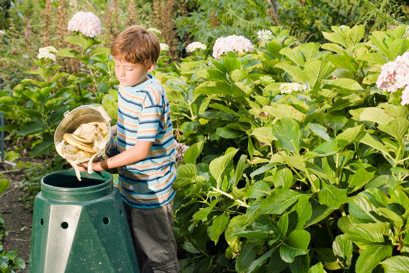 Boy emptying bucket into compost bin